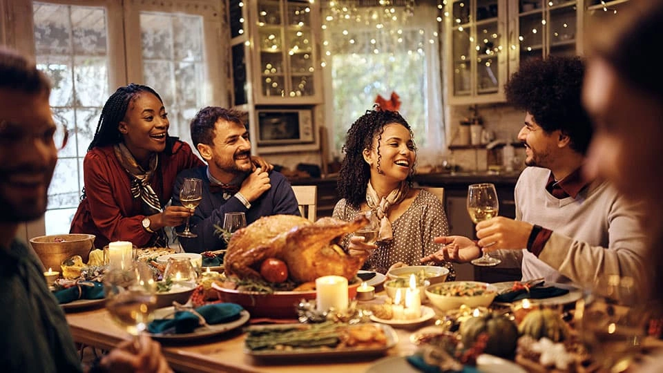 Family sat around a warmly lit table with festive food and candles