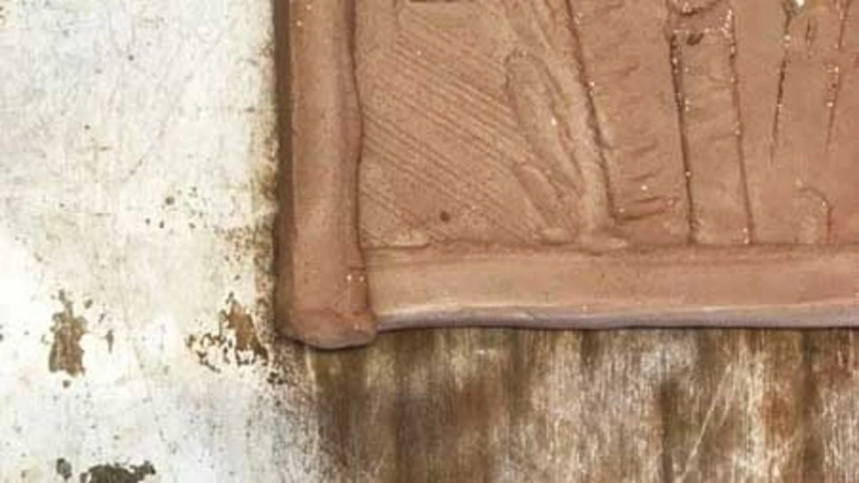 A clay tile set within a wooden frame, showcasing a blend of natural materials and craftsmanship.
