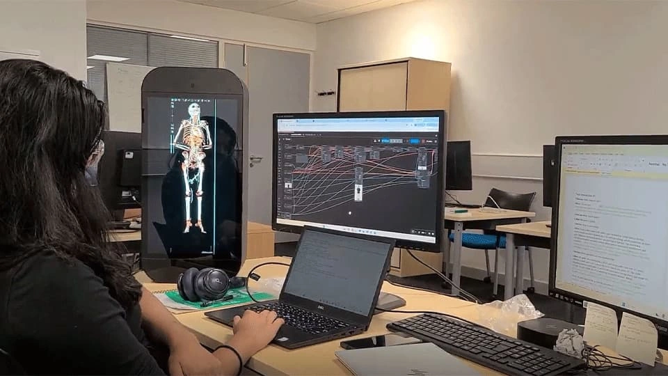 Woman sitting at computer screens showing a skeleton and data