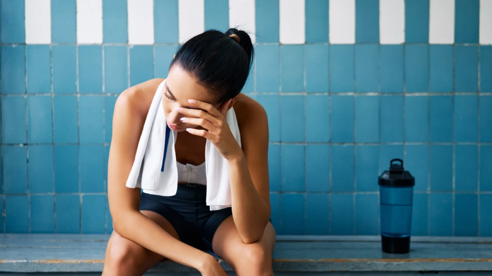 an athlete sitting on a bench looking forlorn