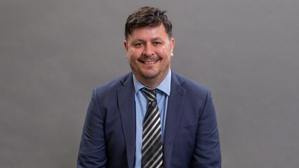 Close-up of Professor Dan Parsons in front of a grey background.