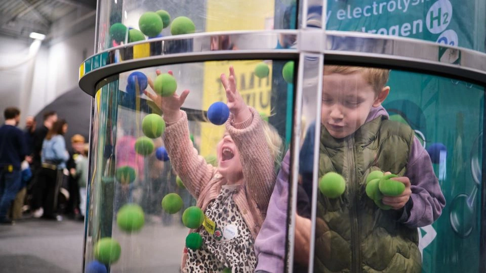 Two children playing inside a Ballnado Grabber Machine.