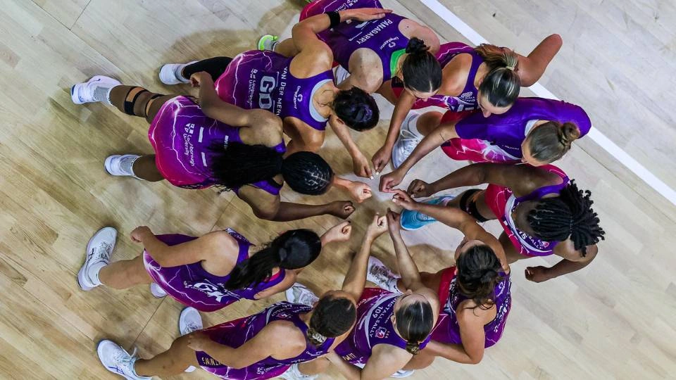 an aerial shot of lightning netball players in a huddle