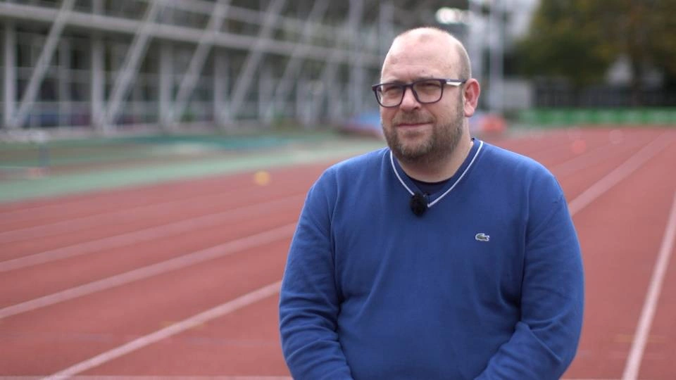 a man sat down with a running track in the background