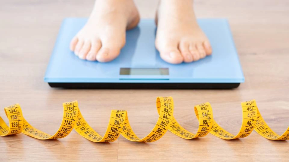 a person standing on weighting scales with a measuring tape laid in front