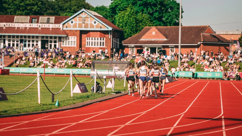 athletes running around a track from distance