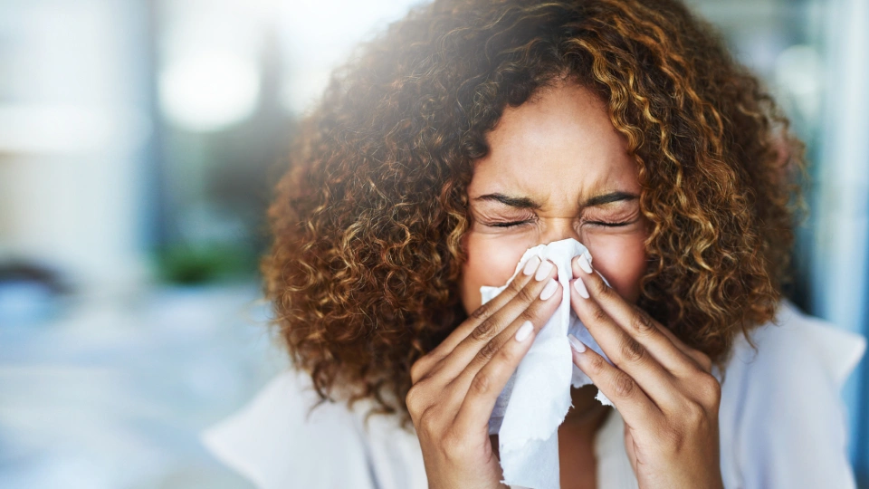 a woman sneezing into a tissue