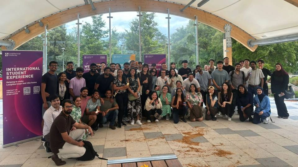 a large group of students and staff stood together smiling at the camera under a pavilion