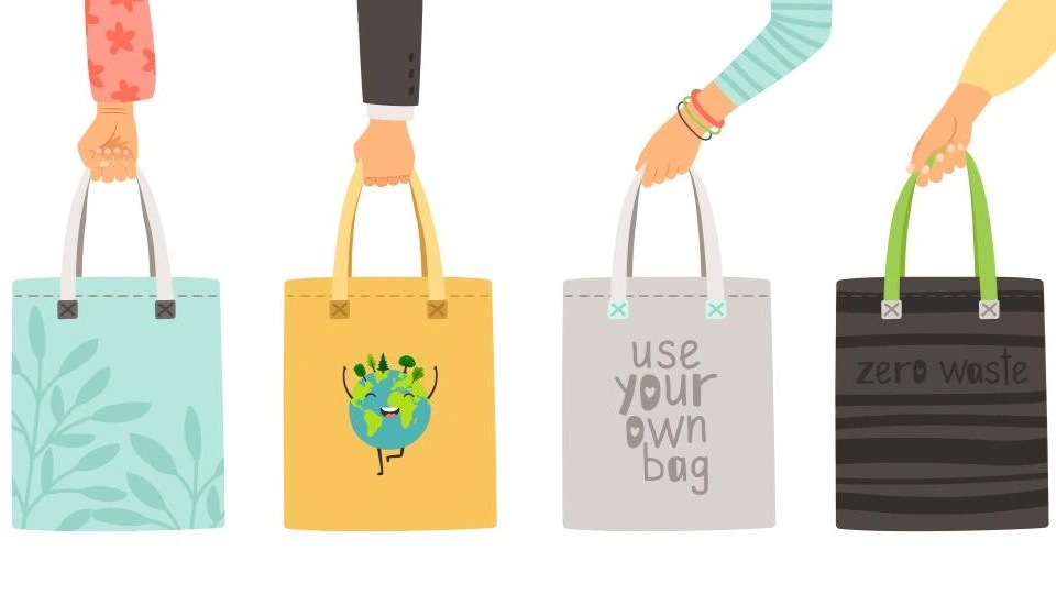 Four reusable tote bags with eco-friendly designs and messages promoting sustainability.