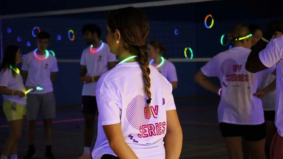Students at Glow Fest 2025 wearing glowstick necklaces in the dark with UV glowing in the background