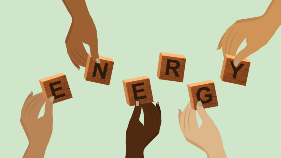 Hands holding wooden blocks that spell the word 'energy' against a pale green background.
