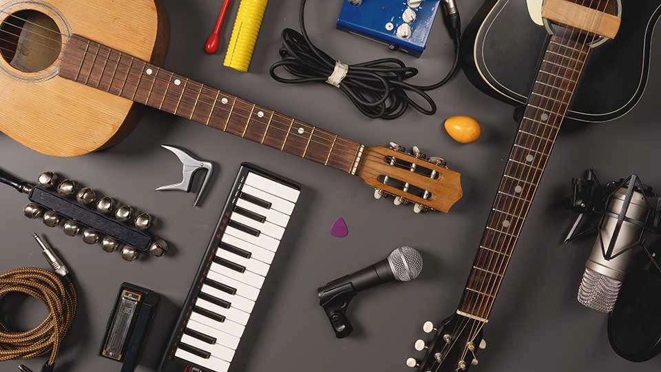 Flat lay of musical instruments and gear including guitars, keyboard, microphone, harmonica, and cables.