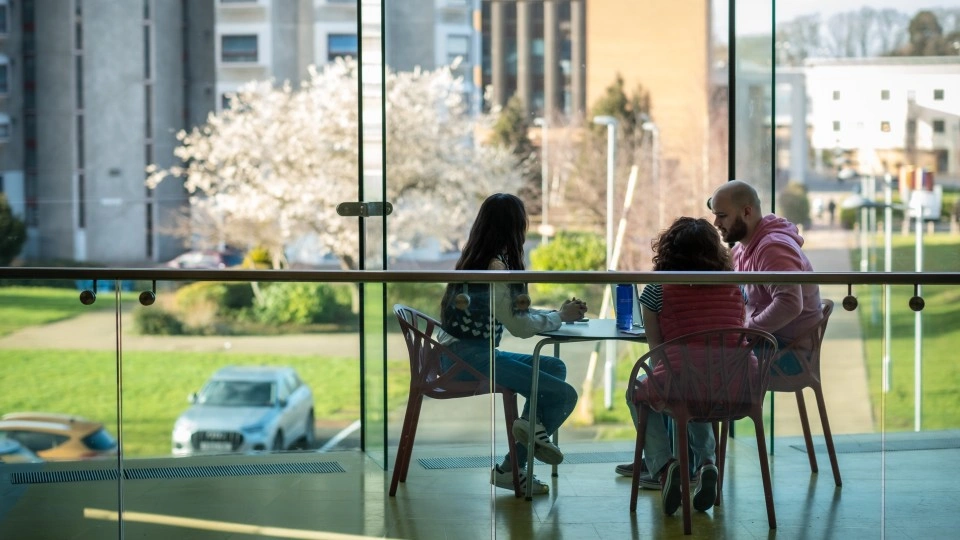 Three students working together on a laptop at a table.