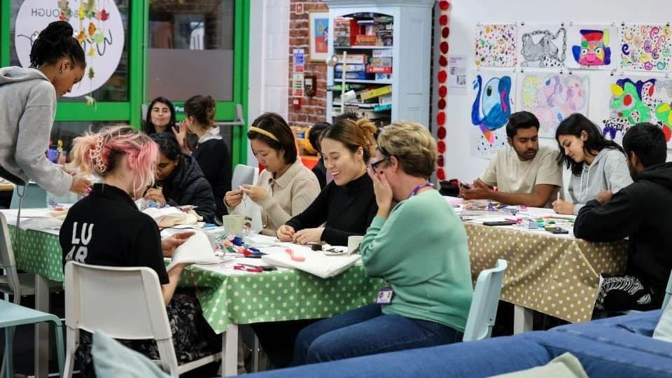 A group of people sat around tables creating art at an LU Arts workshop.