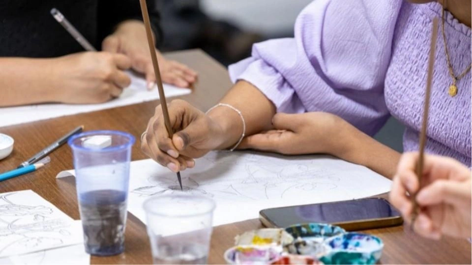Students painting on a wooden table
