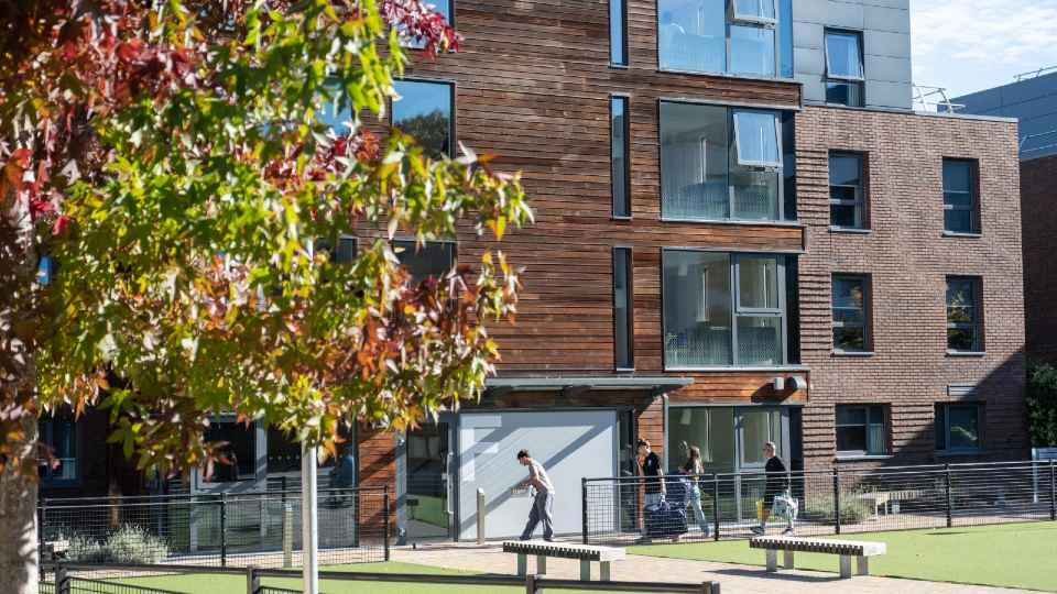 A group of people walking outside of a halls of residence on Loughborough campus.
