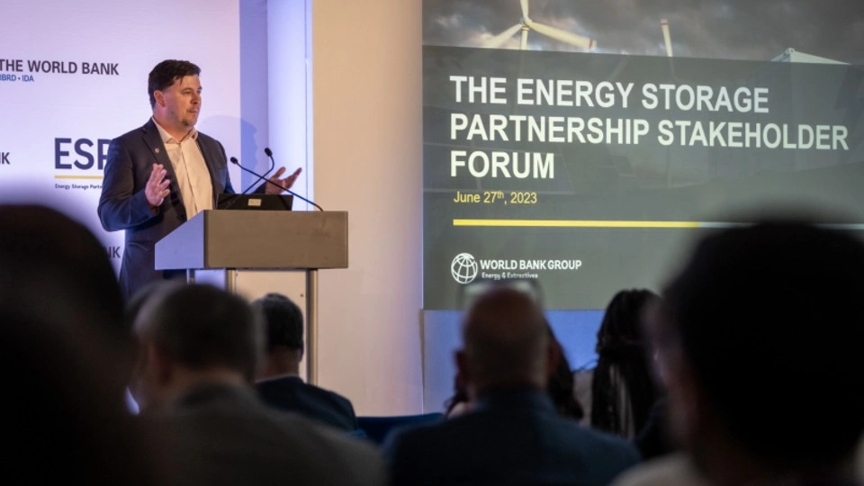 Professor Dan Parsons standing at a lectern addressing the audience. A large presentation screen saying 'The Energy Storage Partnership Stakeholder Forum' is on the right. 