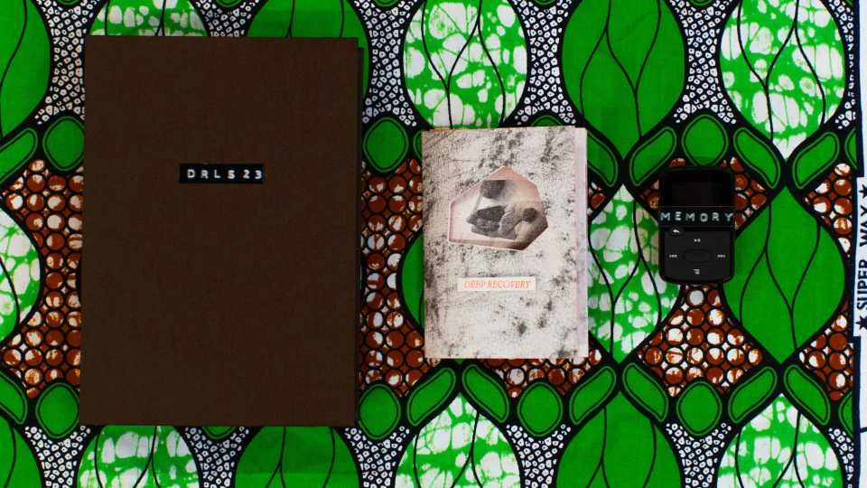A green and brown patterned background with two books on top, one labelled 'Deep Recovery' and a small remote control labelled 'Memory'.