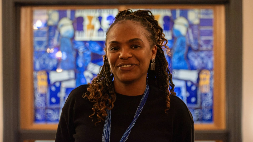 Kedisha Coakley stood in front of her stained glass artwork in Rutland Lounge at Loughborough University
