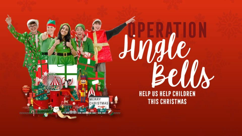 Four people dressed as elves and one as santa, standing behind a pile of toys alongside the text 'Operation Jingle Bells, help us help children this Christmas'.