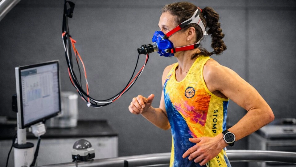 Athlete wearing a respiratory mask whilst running on a treadmill in a laboratory setting.