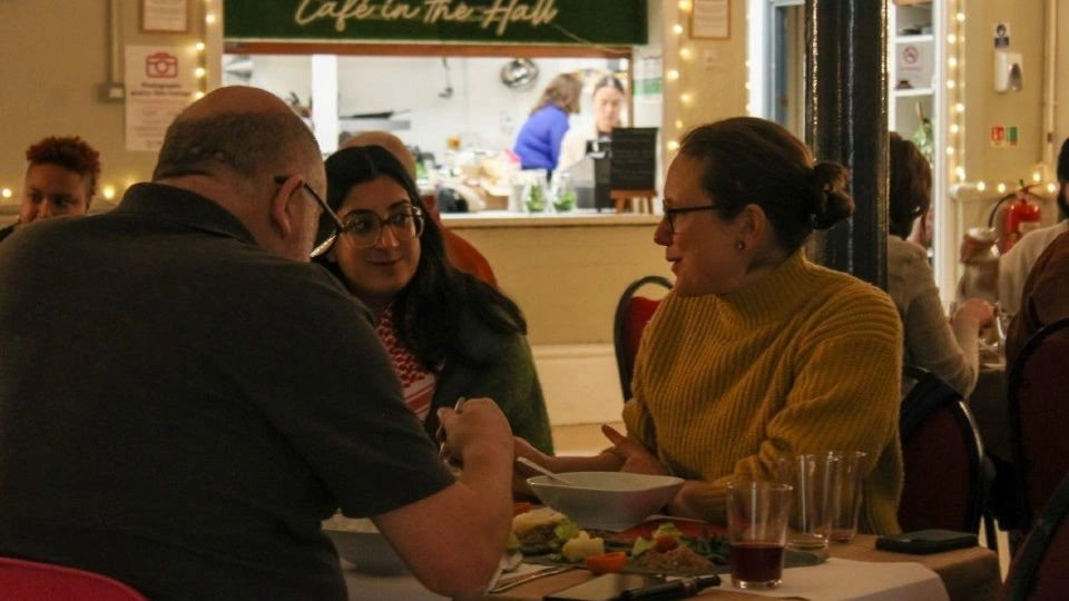 Three people eating and talking at a table.