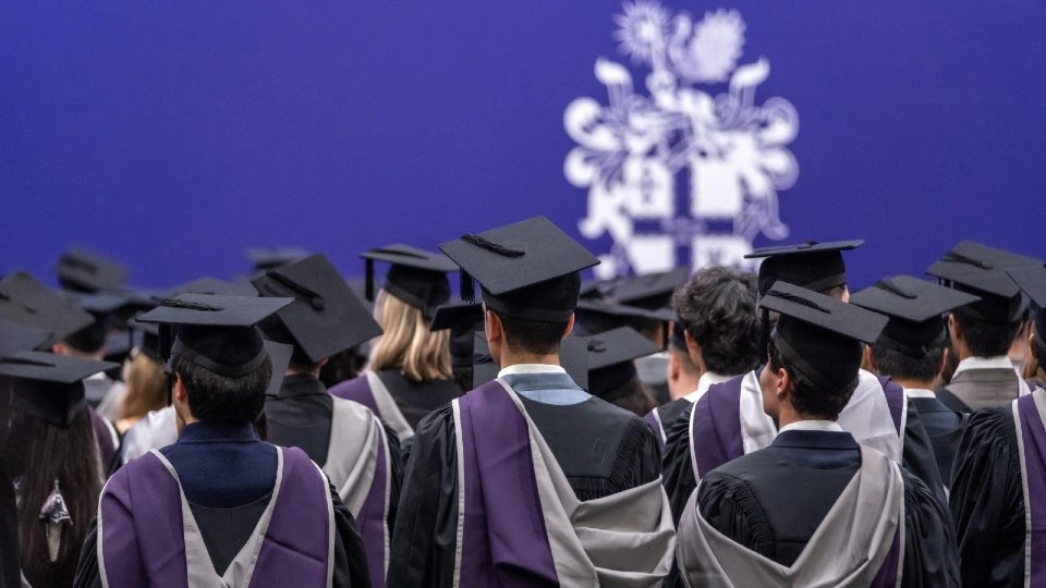 A group of students gathered at a graduation ceremony wearing cap and gowns.