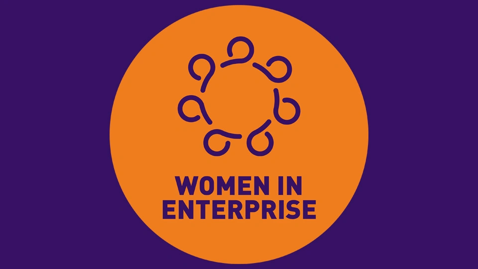 Purple background with an orange circle in the centre and text reading 'Women in Enterprise'.