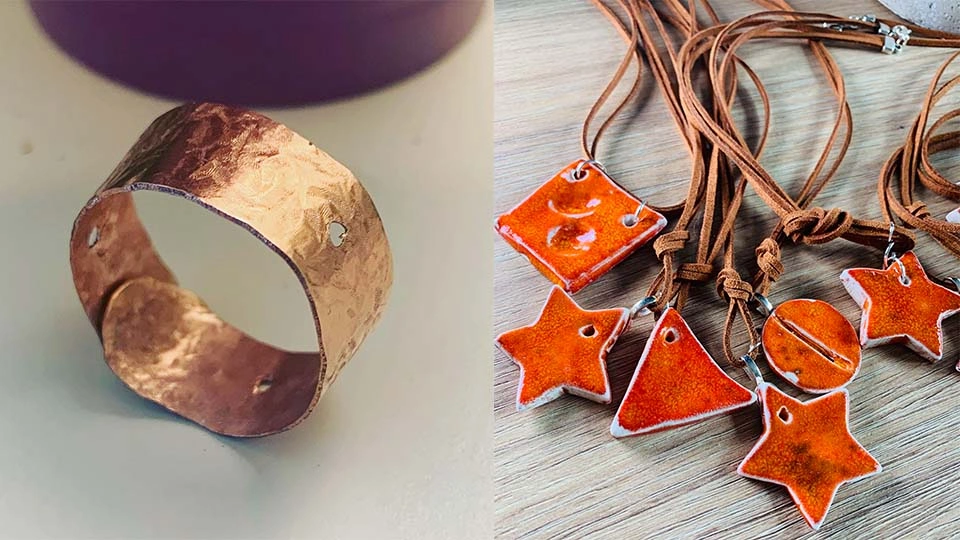 A brass ring propped up on its side and some orange necklaces with different shaped pendants