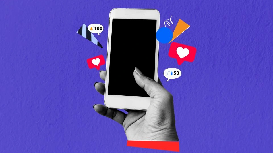 A hand holding a mobile phone with social media icons popping out of the screen.