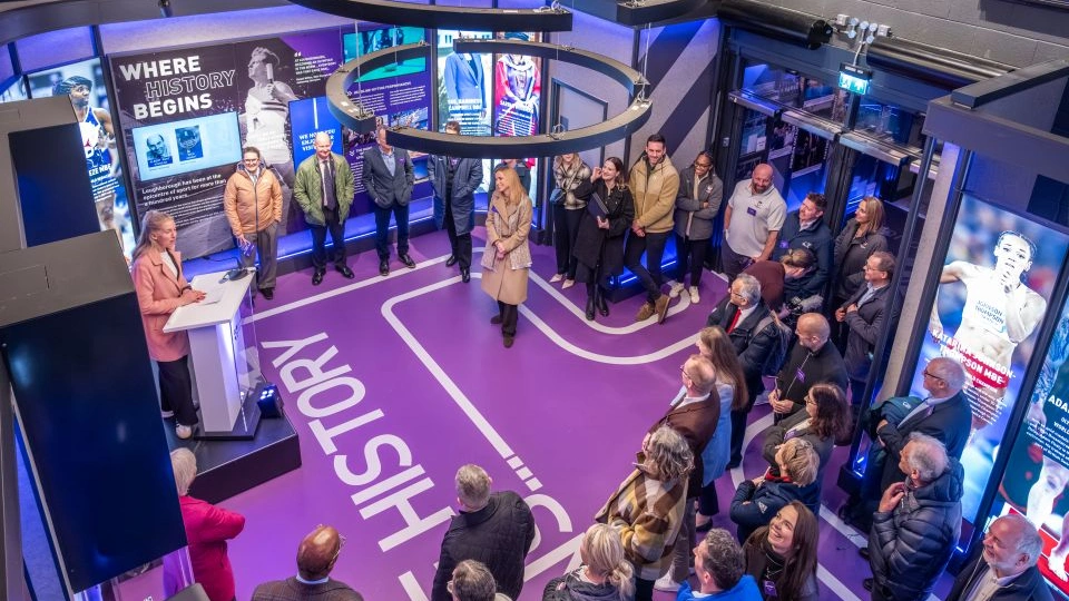 A group of people stand together at the Gateway to Sport entrance to the Sir David Wallace Sports Hall