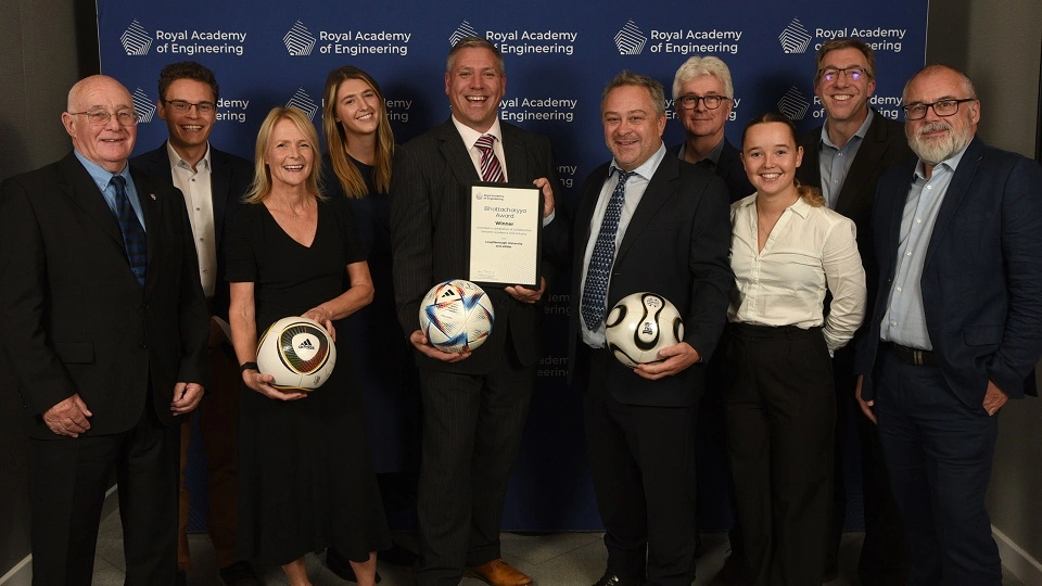A group from Loughborough University and adidas standing together holding the award and footballs.