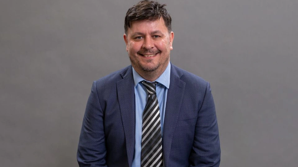 Close-up of Professor Dan Parsons in front of a grey background.