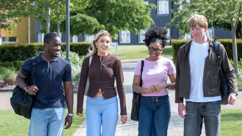 four students walking outside on the Loughborough campus together in a line