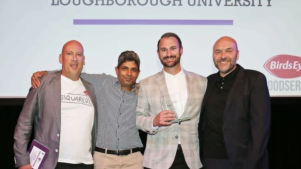 Photo of Tony Clifton from Birds Eye Foodservice, Loughborough colleagues Gagan Kapoor and Darren Harrison, and renowned chef Simon Rimmer all looking at the camera and smiling on stage at the awards evening