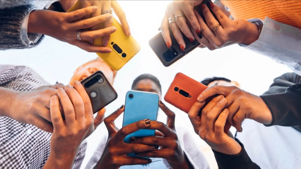 teens stand in a circle ooking at their phones