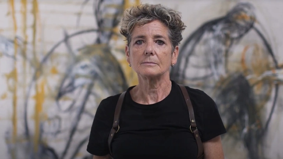 Rachel Gadsden in front of a large white canvas with black markings on it