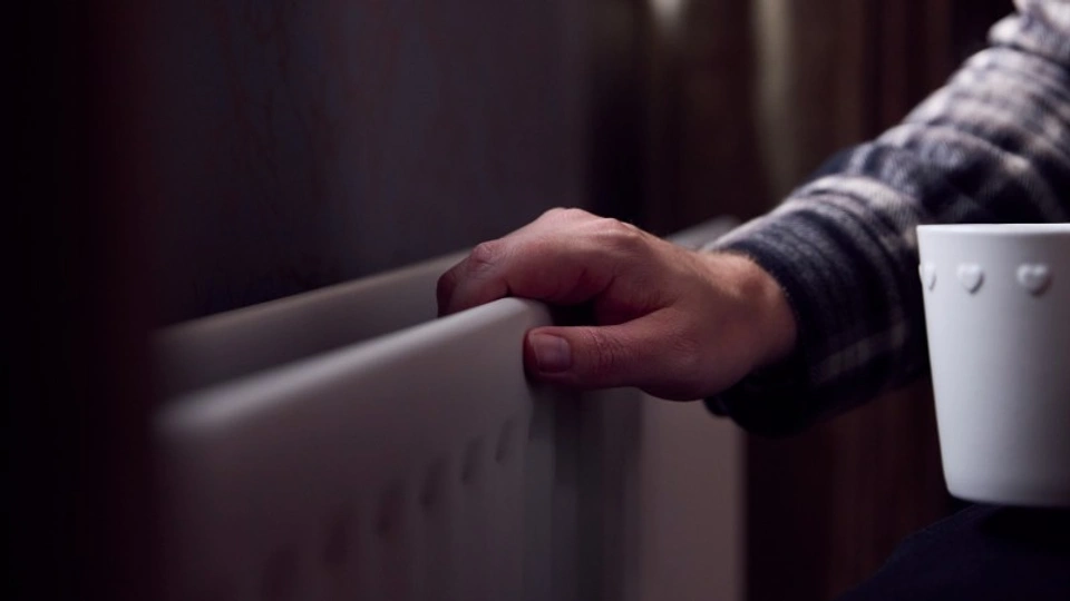 An old hand on a radiator in a gloomy house