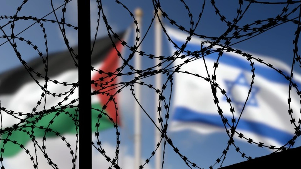 Flags of Israel and Palestine fly behind barbed wire