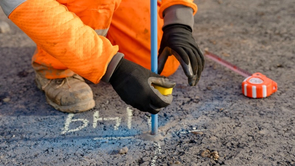 A man plots out markings on a road