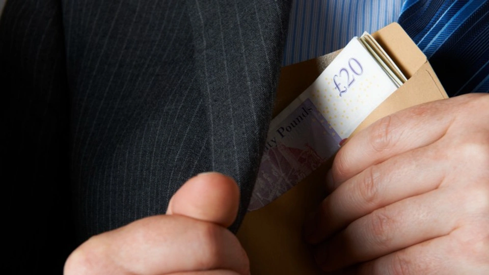 A man puts an envelope of cash in his pocket