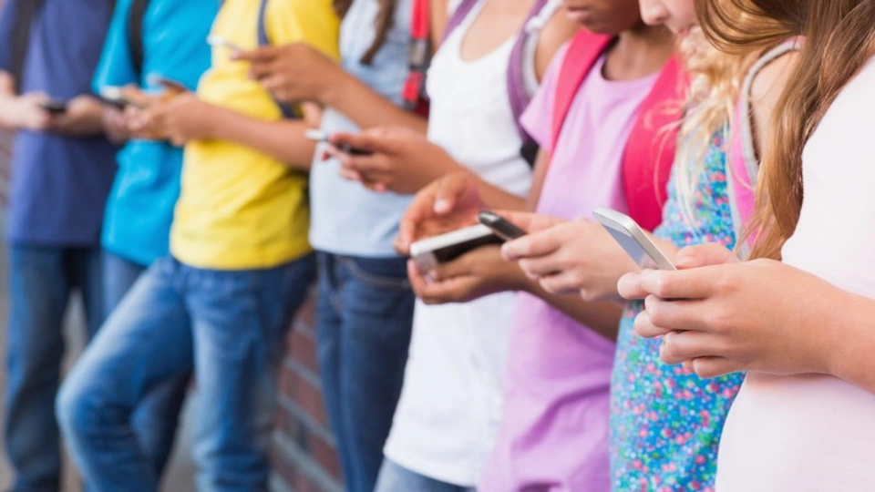 A line of youngsters all looking at the phones