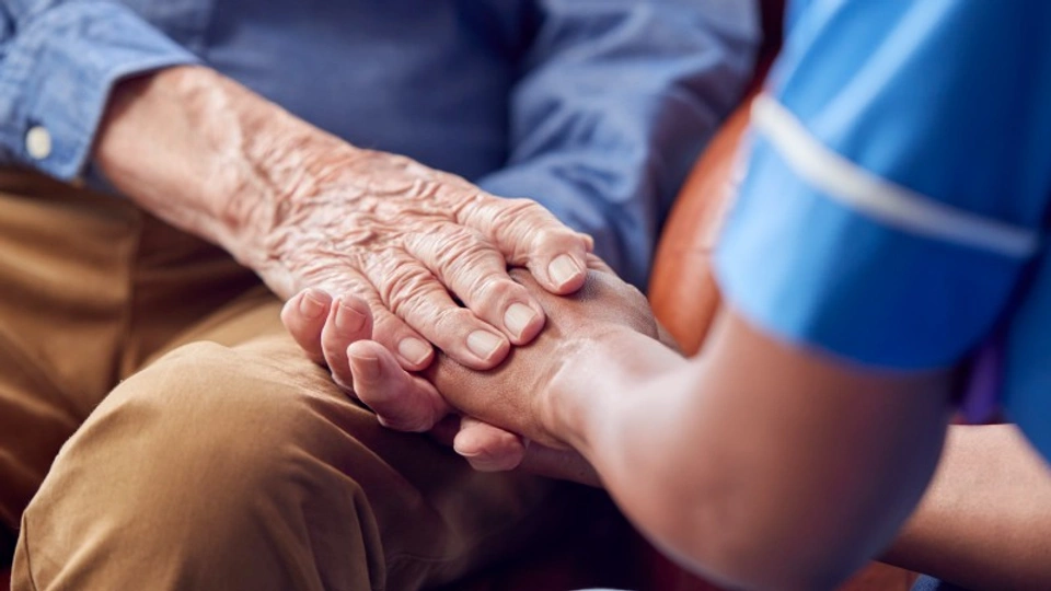 an elderly person holds hands with a nurse