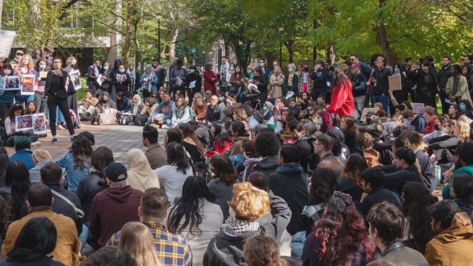 a crowd gathers outside in to listen to someone speak