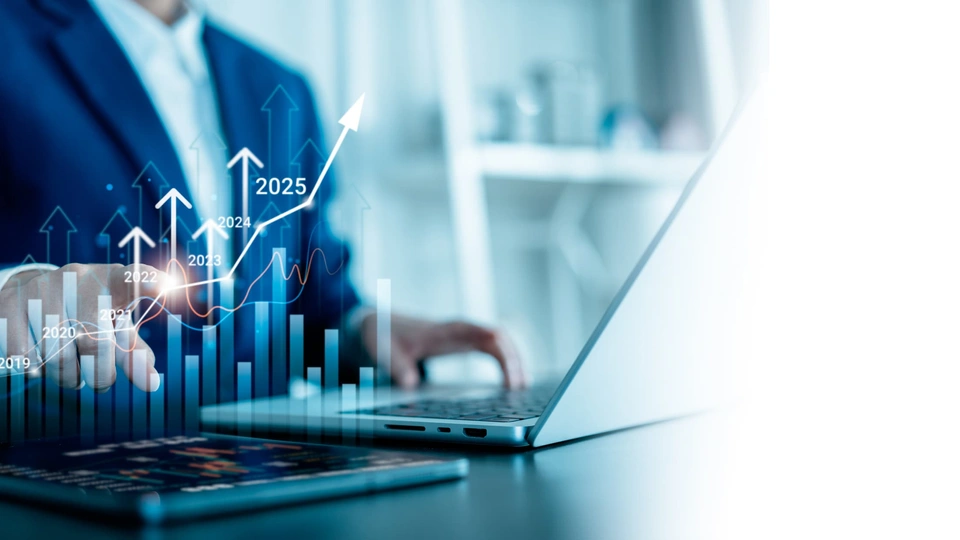 A person sat at a laptop with graphics of increasing bar charts in front of the screen